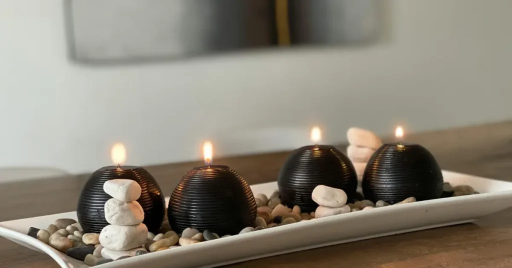 
four black sphere candles on white rectangular tray with river pebbles on dark wood kitchen table