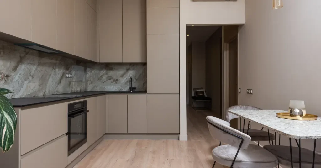 Greige kitchen cabinets with dark stone countertop and backsplash