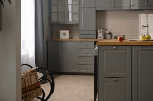 Matte black kitchen cabinets with wood countertop and patterned tile floor