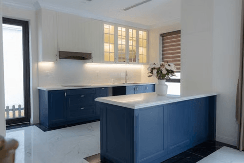 Navy blue kitchen cabinets with white upper cabinets and brass hardware