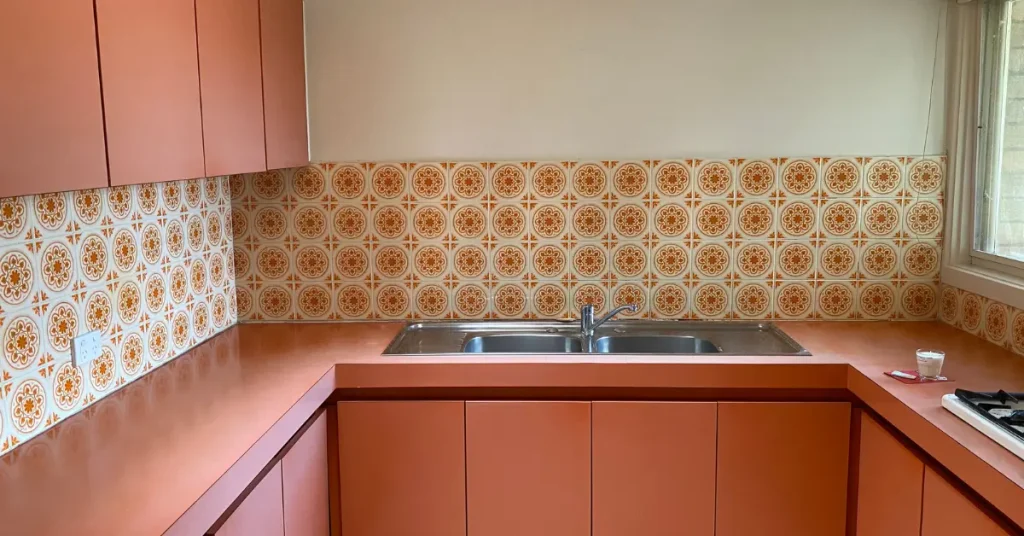 Terracotta kitchen cabinets with matching countertops and patterned backsplash