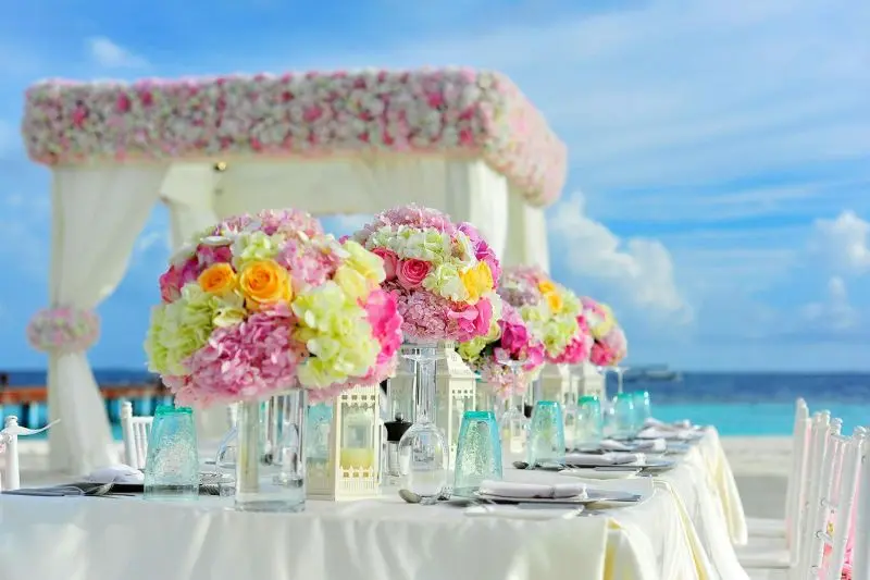 cohesive color palette table setup with pink floral centerpieces teal glasses and white linens for home gathering