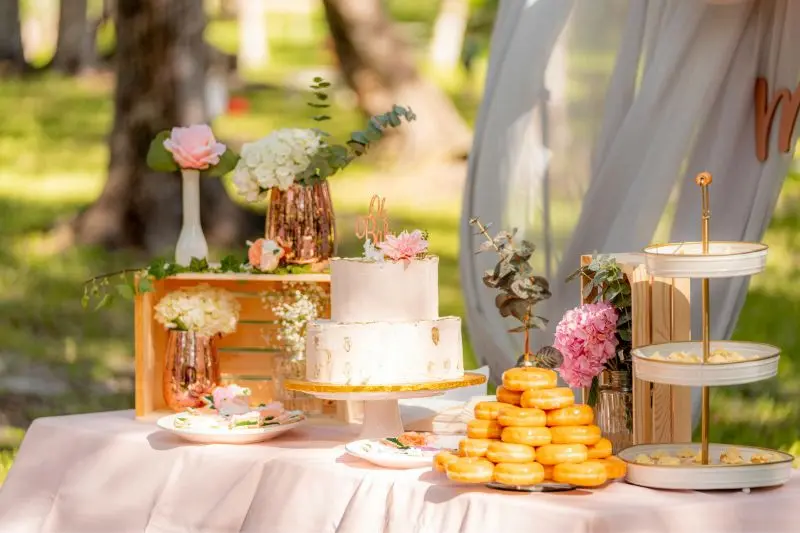 dessert table with tiered cake stand donuts and gold three tier tray at different heights