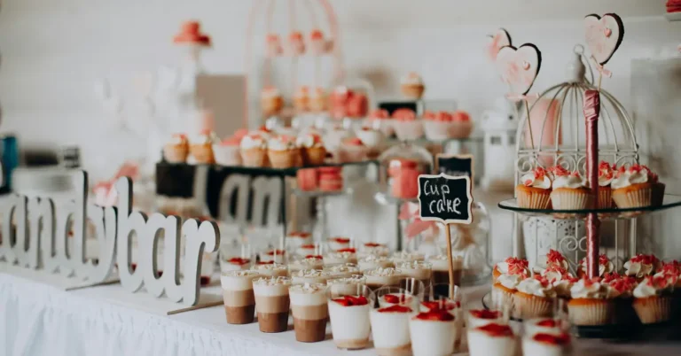 Party dessert table setup featuring mini mousse cups, frosted cupcakes, chalkboard signs, and decorative displays.