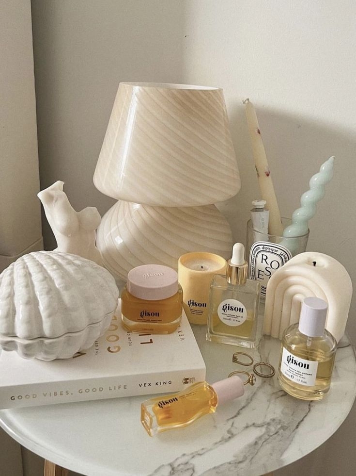 Round marble nightstand styled with a ceramic lamp, candles, and skincare items in a small apartment bedroom
