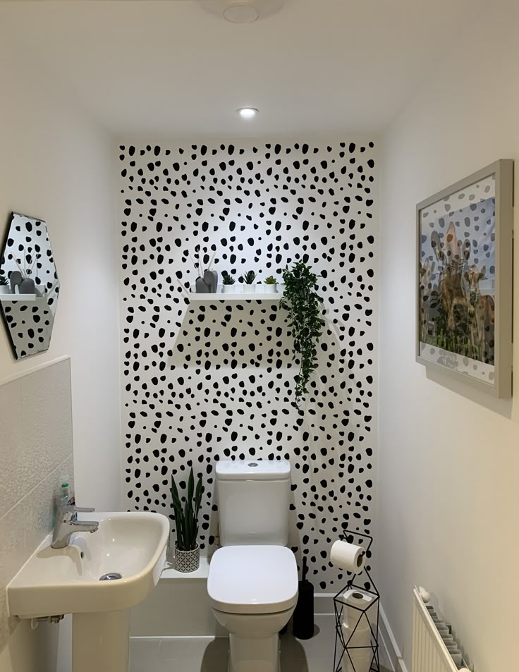 Small bathroom counter styled with a gold and glass soap dispenser, wood tray with soap bars, patterned box with folded towels, and a vase of faux hydrangeas