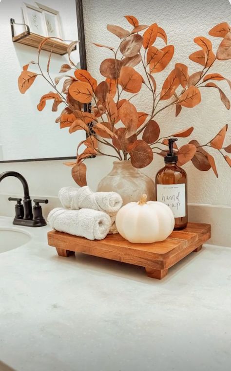 Small wood tray with rolled towels and a mini white pumpkin styled on a bathroom counter for fall