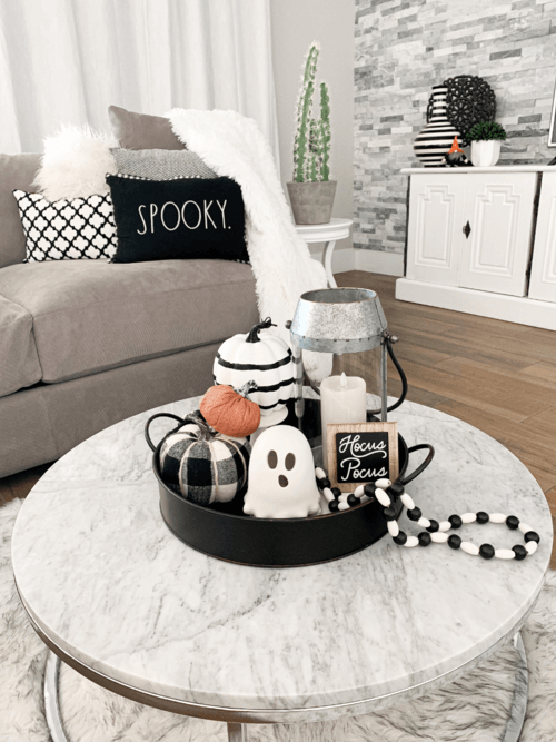 Black and white Halloween tray with a ghost figurine, striped pumpkin, and bead garland