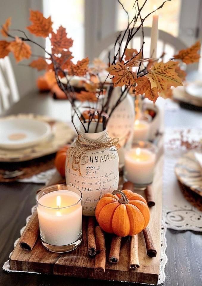 Fall centerpiece with candles, cinnamon sticks, mini pumpkin, and dried leaves in a mason jar on a wood tray