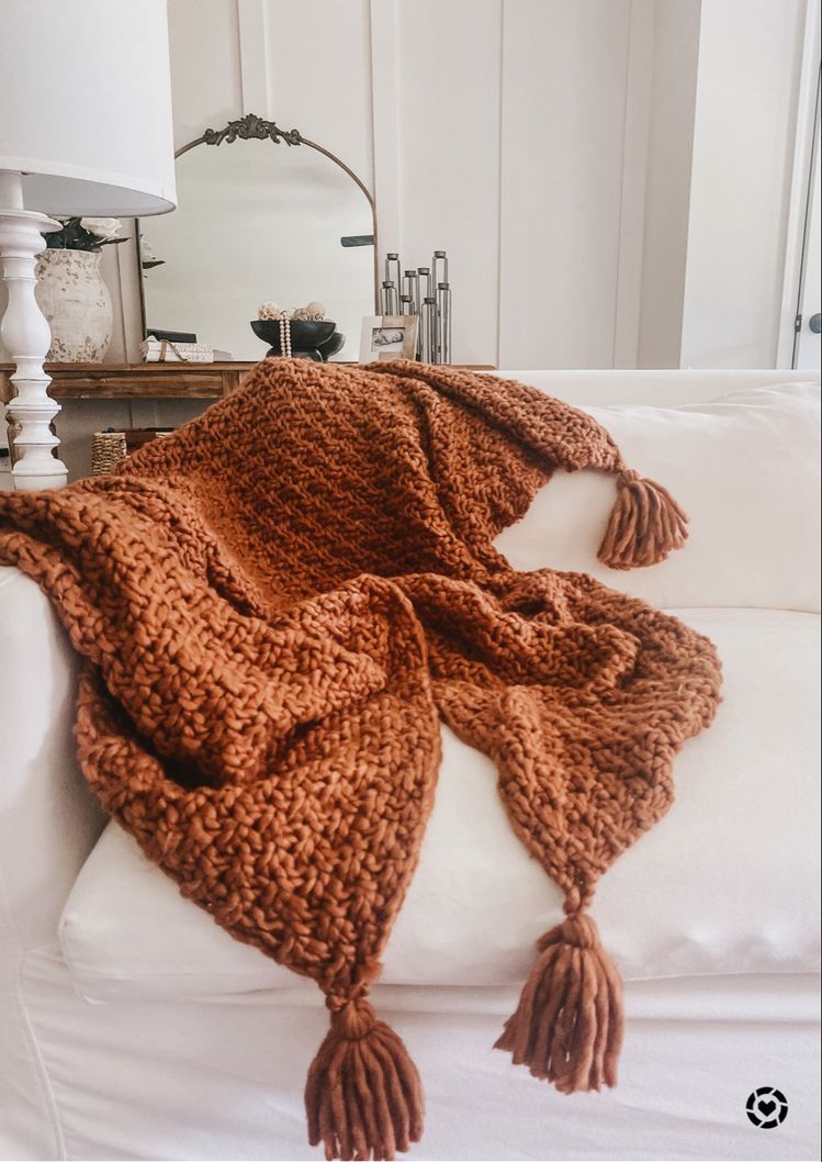 Rust knit throw blanket draped over a couch for fall living room decor
