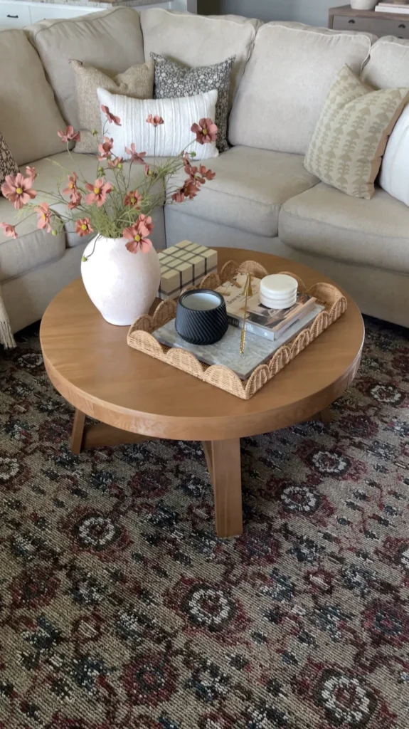 : Woven patterned rug layered under a round coffee table in a fall living room