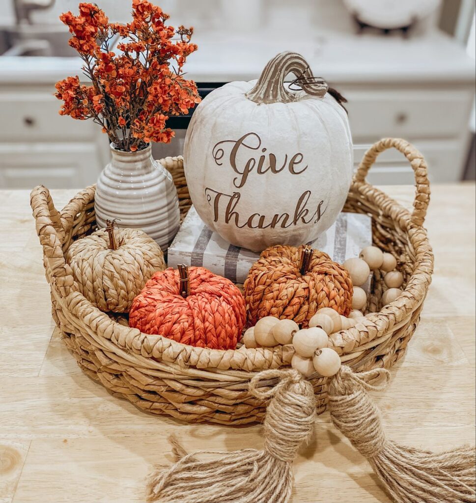 Woven tray styled with mini pumpkins, a dried flower vase, and a Give Thanks pumpkin