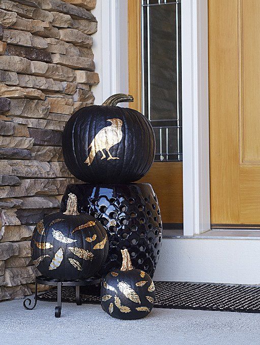 Black pumpkins with gold bird and leaf stencil patterns styled by a front door