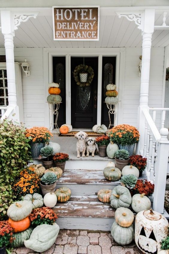 Black pumpkins with gold bird and leaf stencil patterns styled by a front door