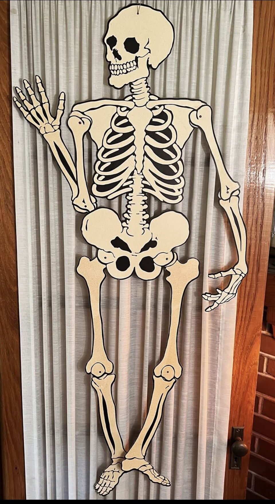 Jointed cardboard skeleton hung on a door, a classic vintage Halloween decor piece