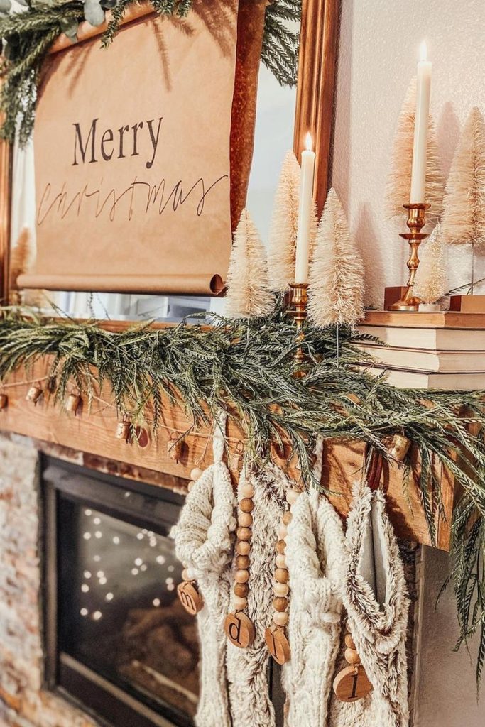Handmade Christmas mantel with cedar garland, brass bells, and wood-bead stockings