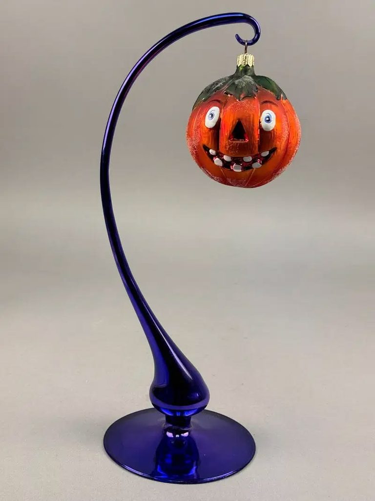 Glass jack-o-lantern ornament hanging from a curved glass stand, a vintage Halloween decor accent
