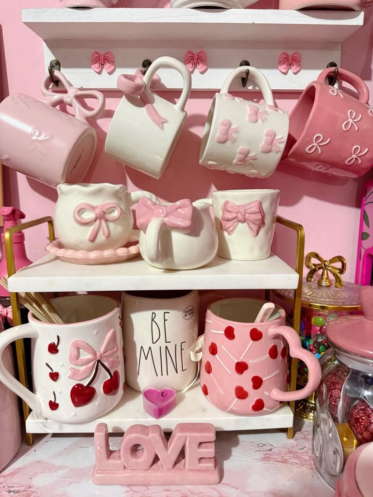 White shelf displaying pink and white novelty mugs shaped like animals and fruit