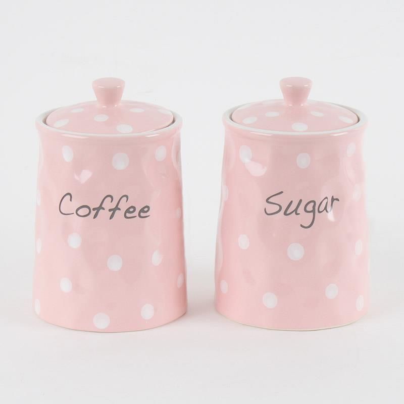 Pink polka dot ceramic canisters labeled coffee and sugar on a white background