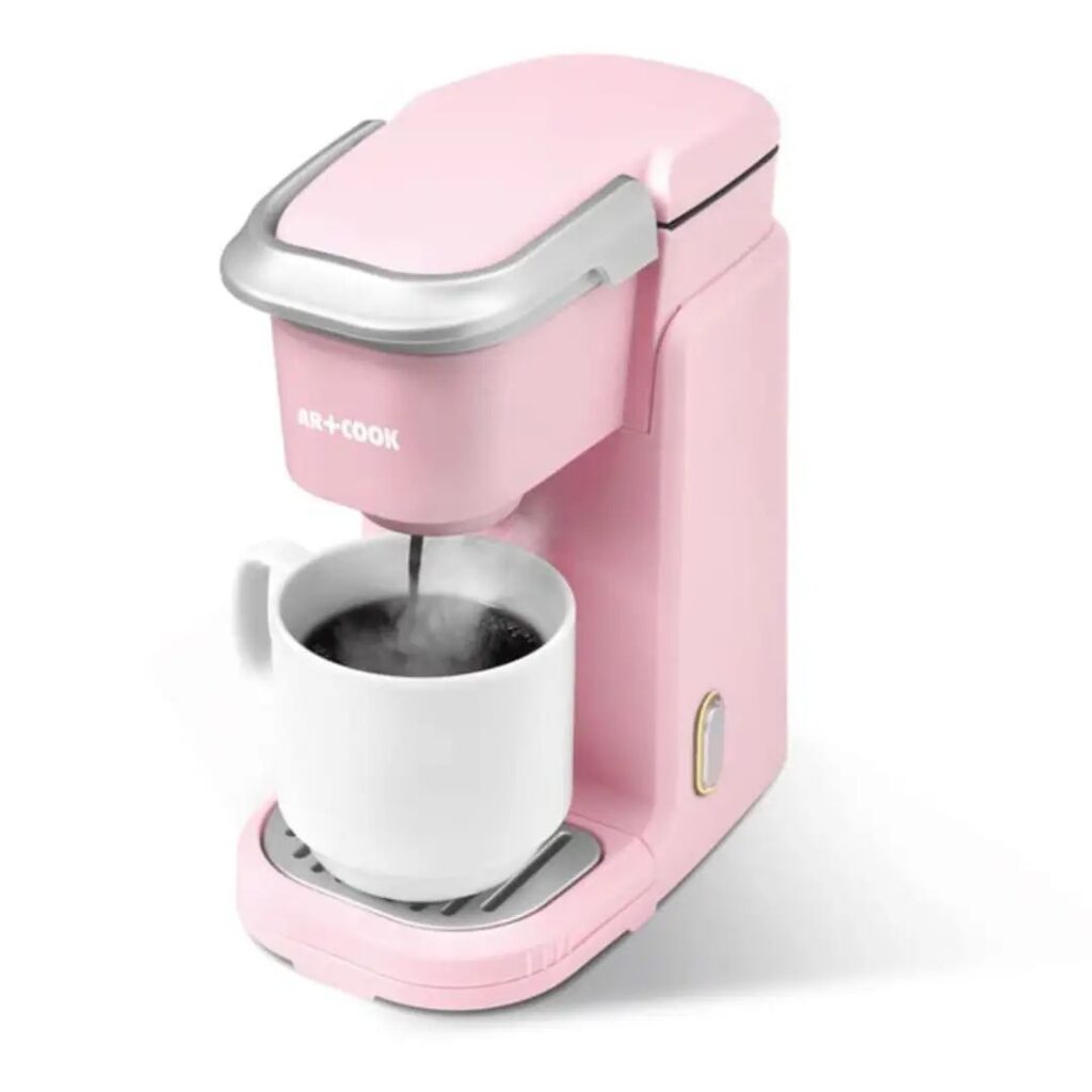 Pink single-serve pod coffee maker brewing into a white mug
