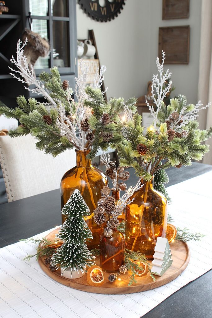 Amber glass bottle vases with pine branches and pinecones as a winter table centerpiece