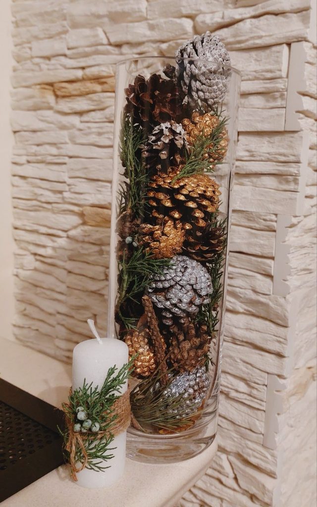 Twine-wrapped pillar candles with cinnamon sticks and dried orange slices on a wood slab winter centerpiece