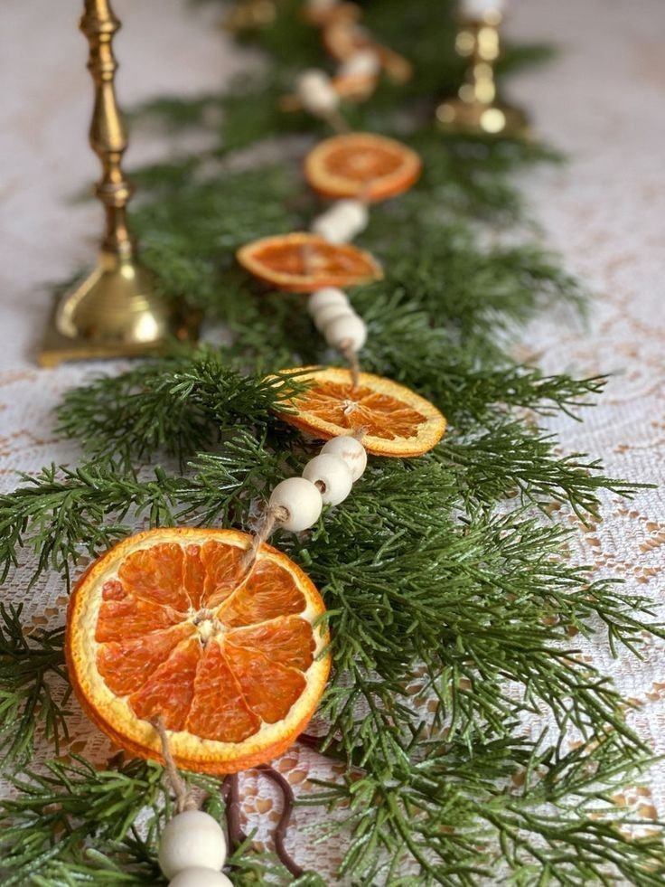 Dried orange slice garland with wood beads draped over greenery as a winter table centerpiece