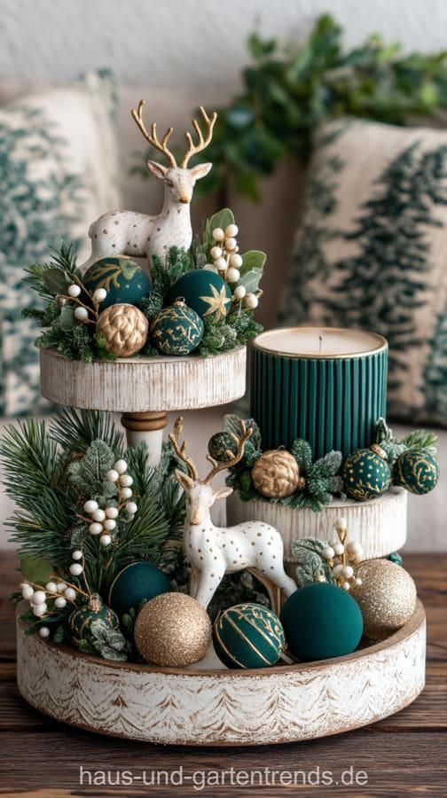 White tiered tray winter centerpiece with gold reindeer figures, dark green and gold ornaments, and a green pillar candle