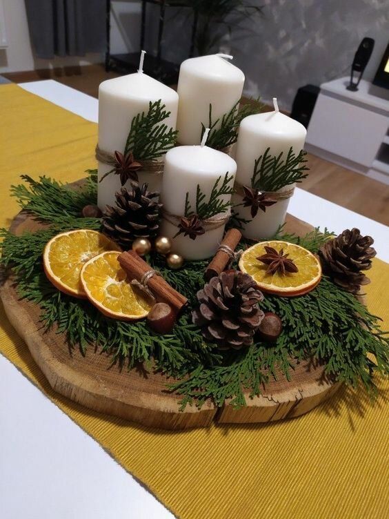 Twine-wrapped pillar candles with cinnamon sticks and dried orange slices on a wood slab winter centerpiece