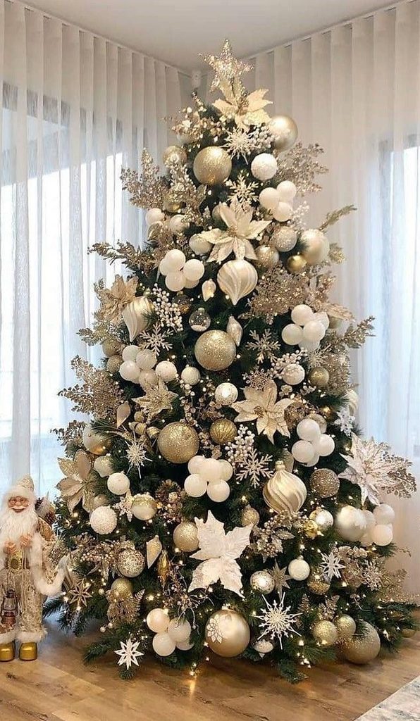 Champagne and white Christmas tree with gold and cream ornaments in front of sheer curtains