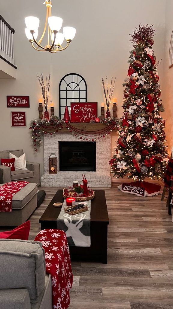 Christmas living room decor ideas with a tall red and white tree, decorated mantel, and red snowflake throws on gray sofas