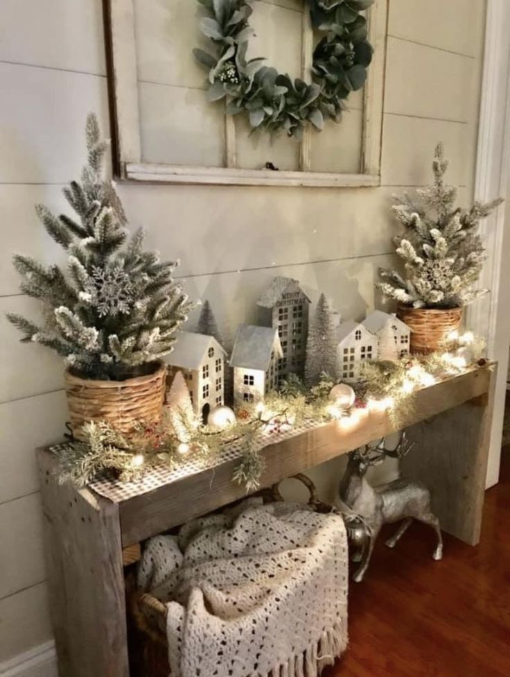 Christmas village display on a console table with houses set on a snowy hill made from a white faux fur throw