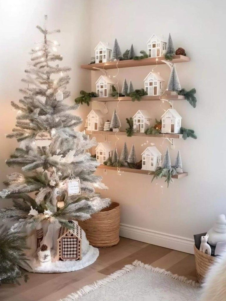 Floating shelves holding white Christmas village houses and frosted bottle brush trees in a corner by a flocked tree