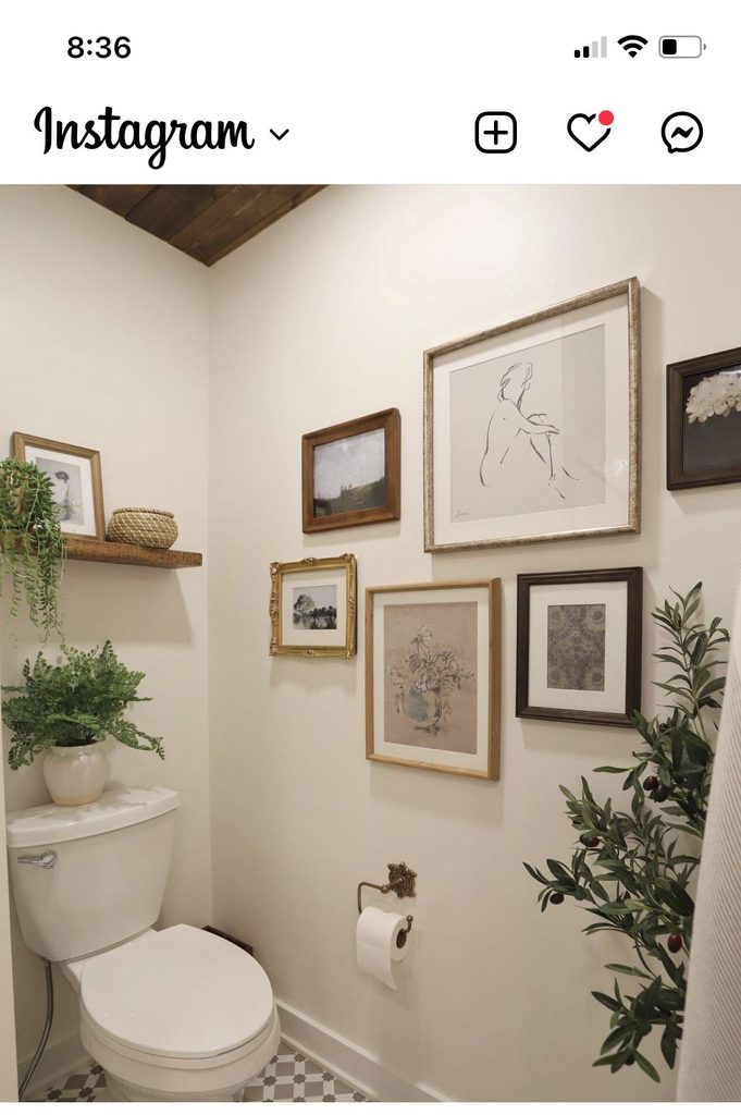 Gallery wall of mixed wood, gold and dark frames next to a toilet in a small toilet room with a wood ceiling