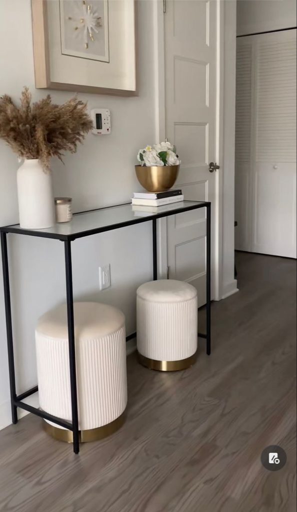 black metal glass-top console table with two ribbed ottomans tucked underneath, small entryway table decor