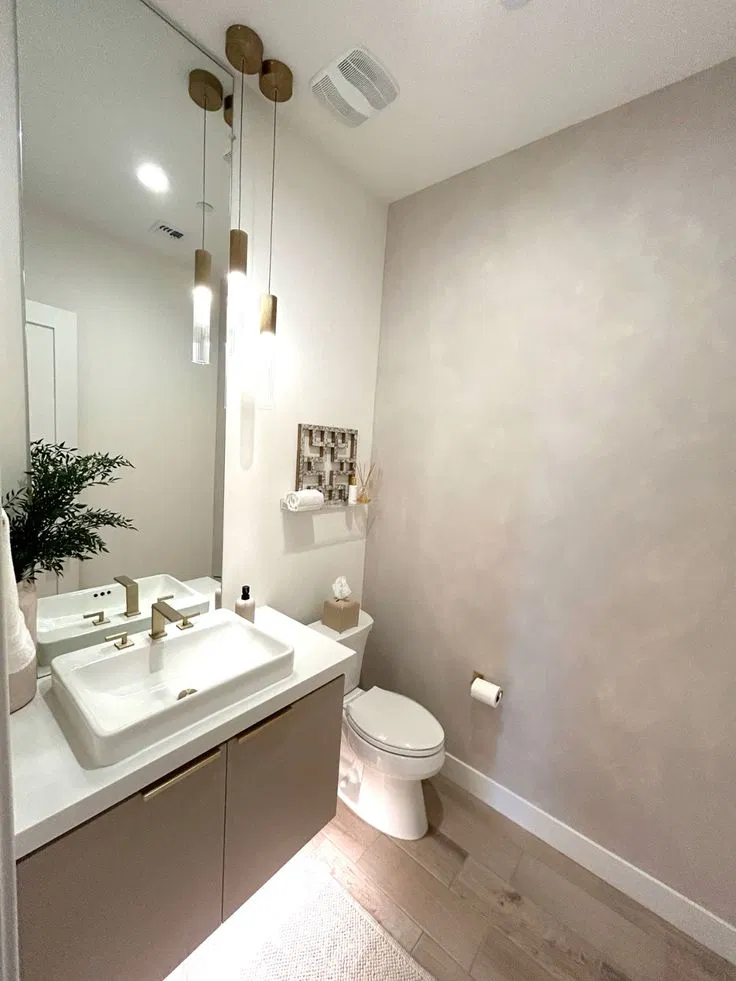 Soft cloudy limewash style taupe wall in a powder room with a white toilet and a small wall shelf