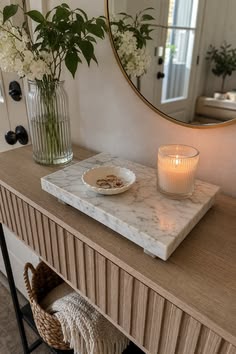 marble tray with a small dish and a candle on a fluted wood console table in a small entryway