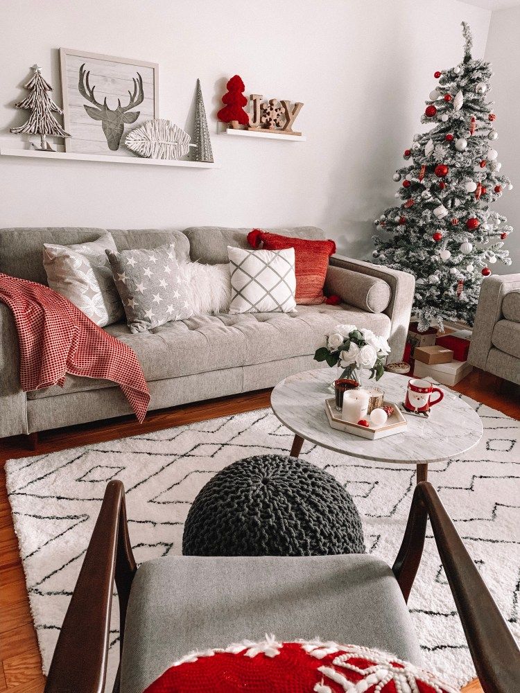 Small flocked Christmas tree in the corner of a living room with red and white ornaments