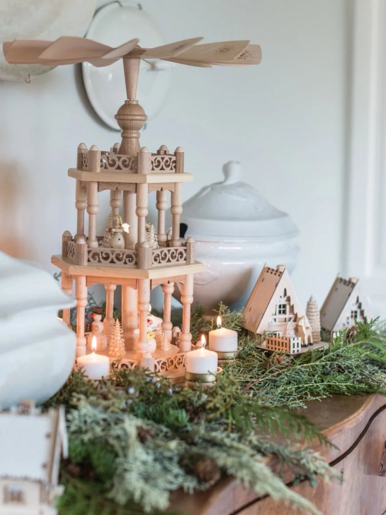 Natural wood Christmas village houses on a bed of fresh evergreen branches with no snow