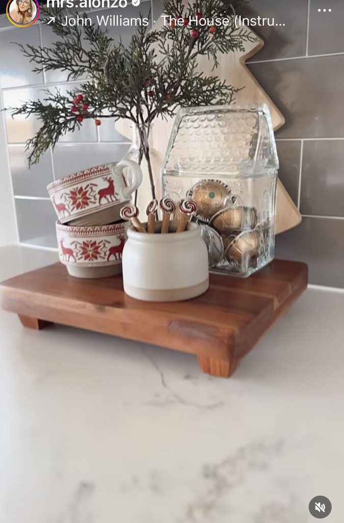 Wood riser with red reindeer mugs, candy cane stirrers and a glass house jar of coffee pods